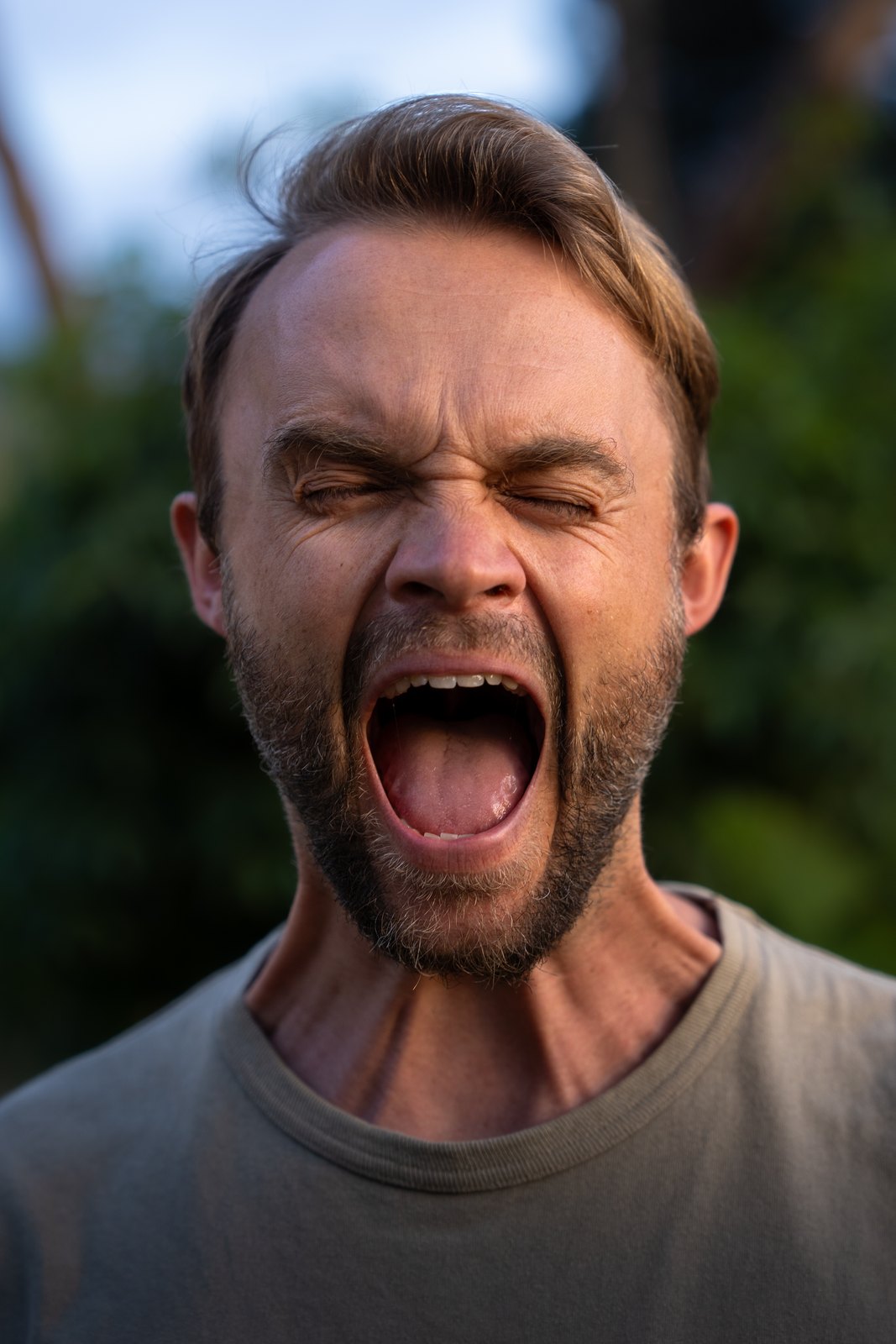 Man shouting with his eyes closed, outdoors
