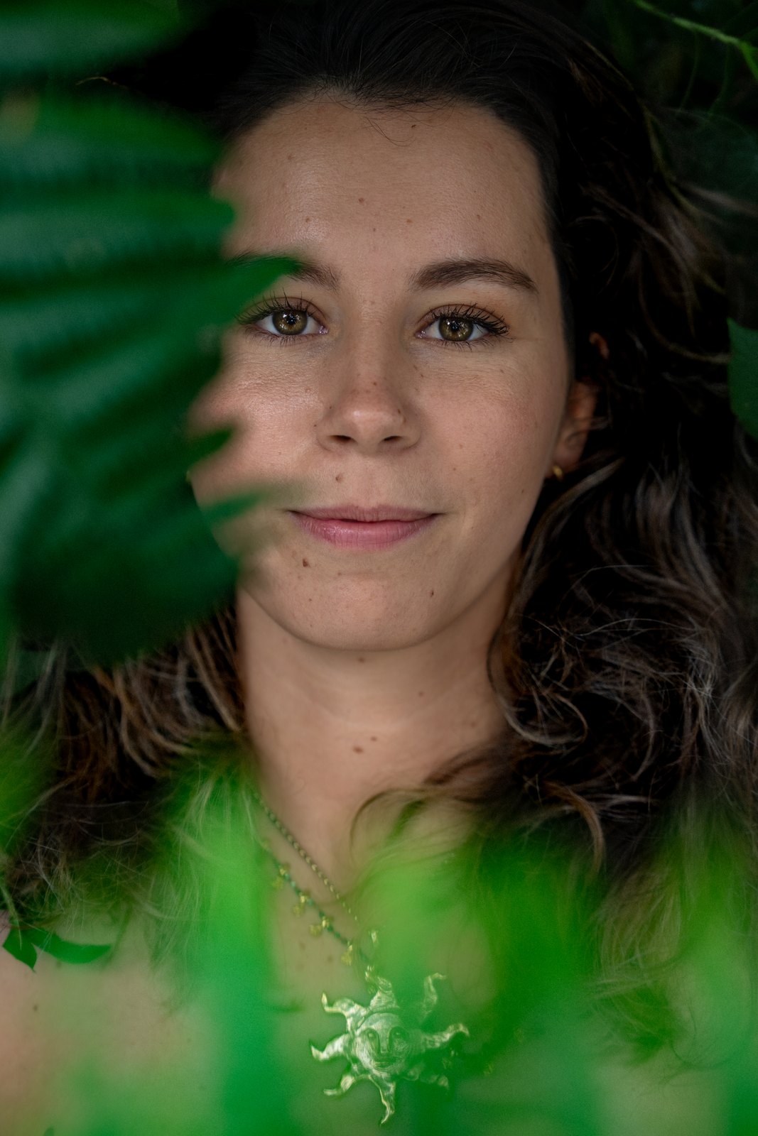 Close portrait of a woman framed by green leaves