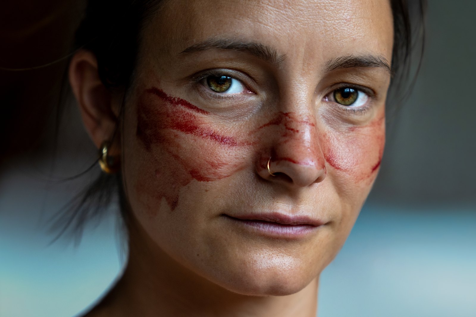 Close portrait of a woman with red paint across her cheeks