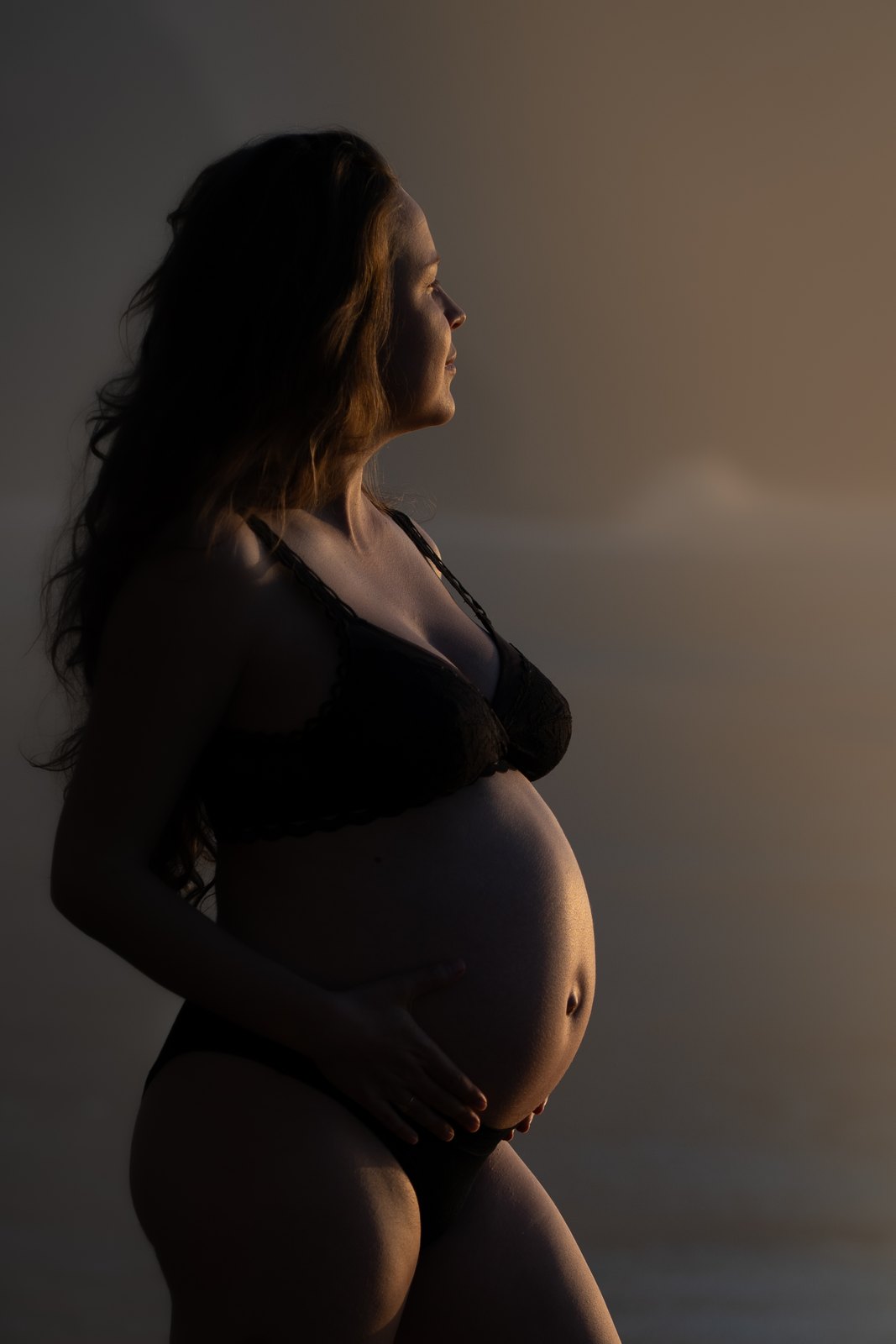 Silhouette of a pregnant woman in soft window light