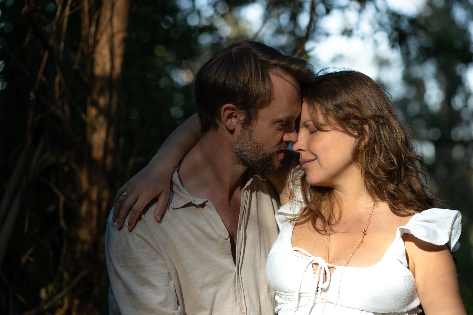 Couple touching foreheads among the trees
