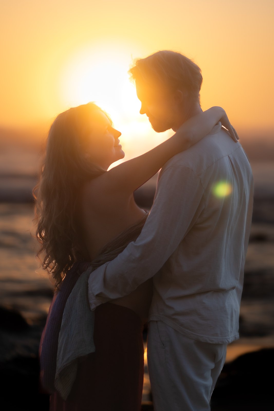 Pregnant woman embracing her partner in the last light of the day